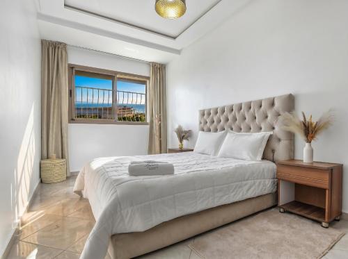 a white bedroom with a large bed and a window at White Majorelle Azul in Tamraght Ouzdar