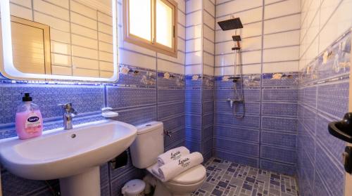 a blue tiled bathroom with a sink and a toilet at White Majorelle Azul in Tamraght Ouzdar