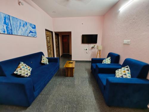 a living room with two blue couches and a tv at Hamsa Farmstay - 2BHK AC Homestay in Mysore