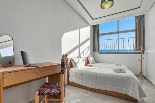 a bedroom with a bed and a desk with a computer at White Majorelle Horizon in Tamraght Ouzdar