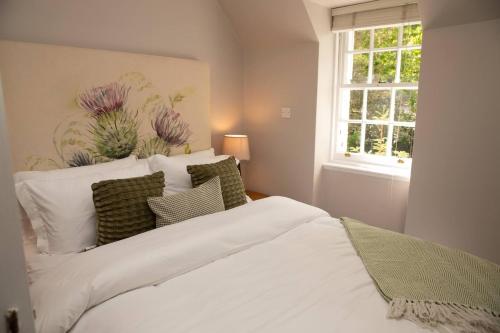a bedroom with a white bed with pillows and a window at Snow Cottage, Old Aberdeen, 3 bedroom luxury in Aberdeen