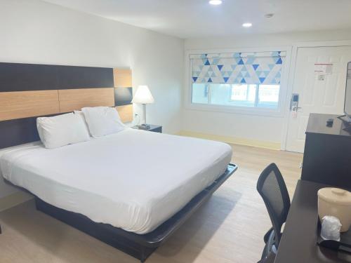 a bedroom with a large white bed and a desk at Bourne Bridge Inn Former Eastern Inn in Bourne