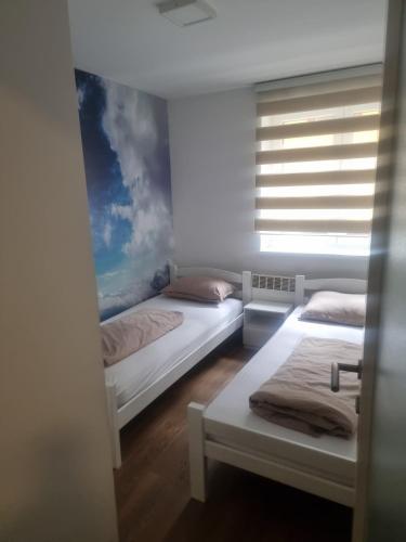 a bedroom with two beds and a window with a painting at Apartman Katedrala in Sarajevo