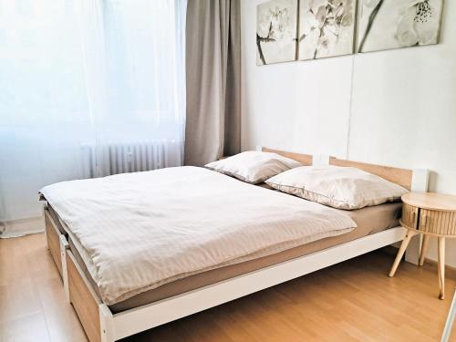 a bed in a white room with a table at Metro Budějovická apartment in Prague