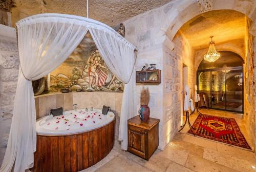 a bathroom with a wooden tub in a room with a stone wall at Cappa Via Cave Hotel in Ürgüp
