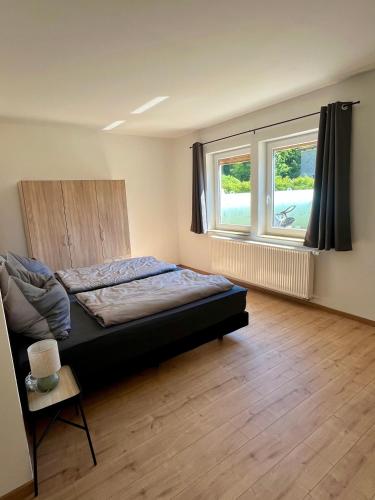 a bedroom with a bed and two windows at Ferienwohnung in der Langenau in Lichtenfels
