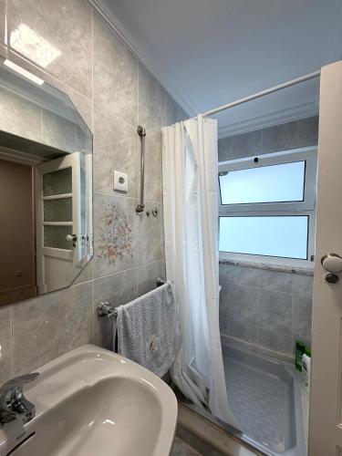 a bathroom with a sink and a shower with a window at Casa da Linha in Caminha