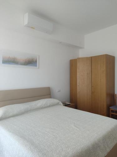 a bedroom with a white bed and a wooden cabinet at Da Fede al mare in Moneglia