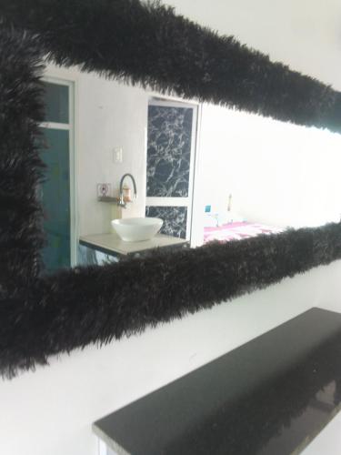 a mirror with black fur on a wall with a sink at Casa suites golden in Tonsupa