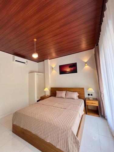a bedroom with a large bed with a wooden ceiling at KUTA GLORI Homestay in Kuta Lombok