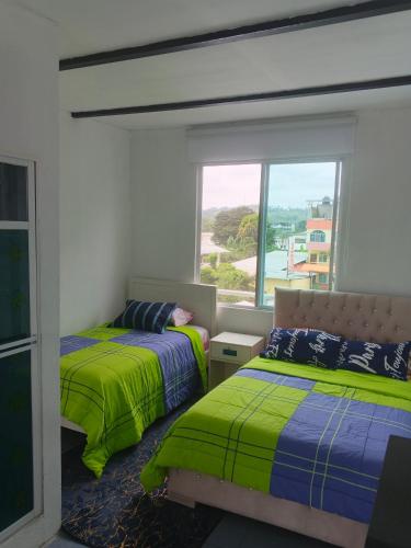 a bedroom with two beds and a window at Casa suites golden in Tonsupa