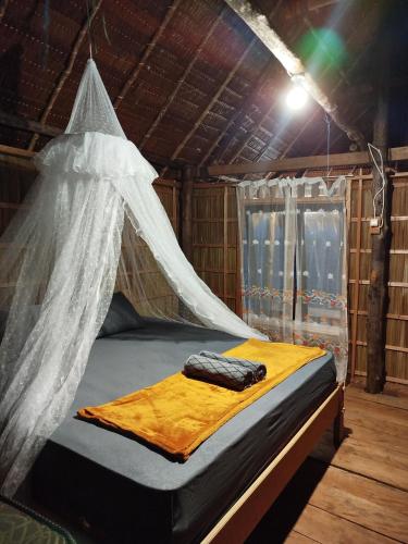 a bed with a mosquito net in a room at Batanta Panorama Homestay in Dayang