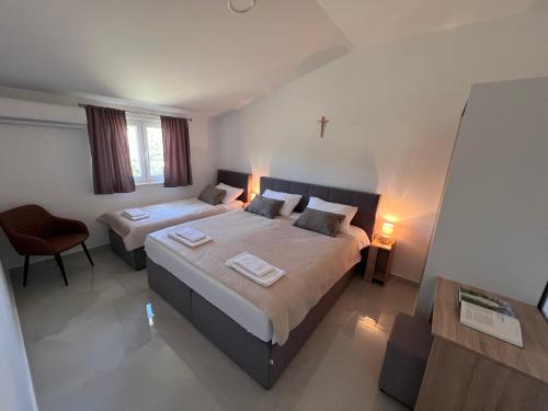 a large bedroom with two beds and a chair at ROOMS Međugorje in Međugorje