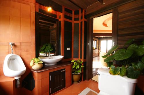 a bathroom with a sink and a urinal and plants at Sea Breeze Resort - SHA Plus in Haad Rin