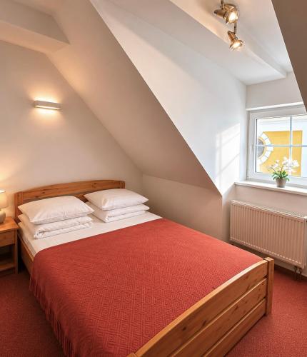 a bedroom with a large bed with a red blanket at Hotel Marislav in Češnovice