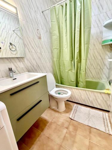 a bathroom with a toilet and a green shower curtain at SiCasa Punta Prima in Punta Prima