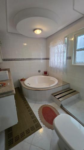 a white bathroom with a tub and a toilet at Di Fronte Al Bosco in Santa Teresa