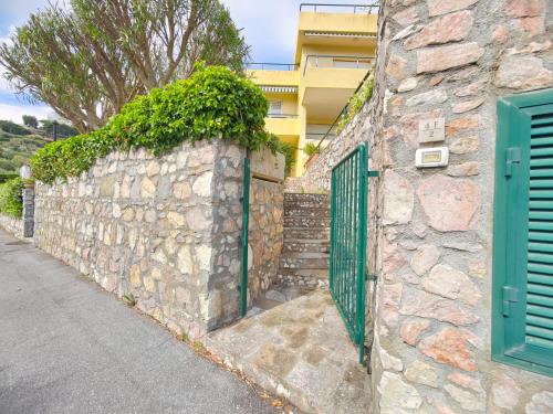 a stone wall with a green gate and a building at Rivierarent Il Giardino Del Navigatore in Finale Ligure