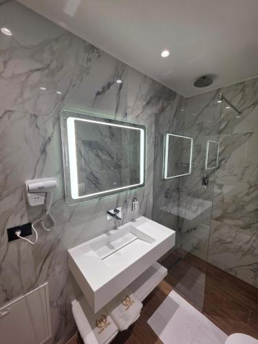 a bathroom with a white sink and a shower at Haris Hotel & Suites in Vlorë