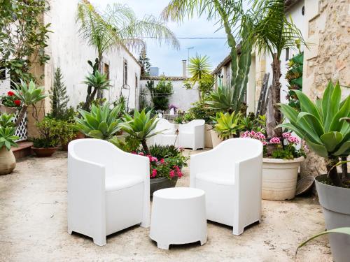 a garden with white chairs and potted plants at A Lumia in Noto