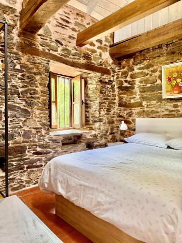 a bedroom with a large bed in a stone wall at CASA FOLIBAR-Encanto rural entre piedra y madera Valle del Silencio in Manzanedo de Valdueza