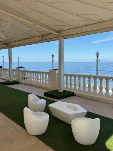 a room with two white chairs and the ocean at Hotel Ariana in Marine du Miomo