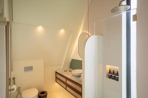 a white bathroom with a sink and a toilet at Hotel Together Bali in Uluwatu