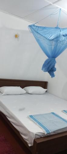 a bed with a blue umbrella on top of it at QUEEN SASTINA guest house in Nilaveli