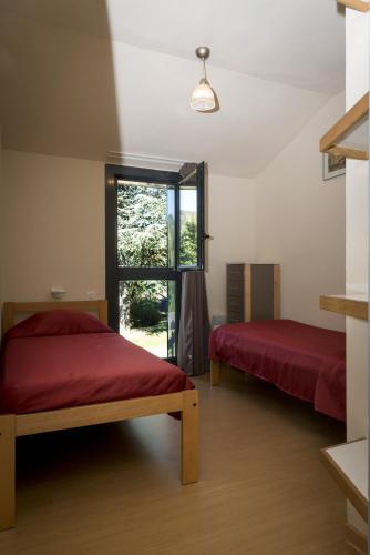 two beds in a room with a window at Domaine Aigoual Cevennes in Meyrueis