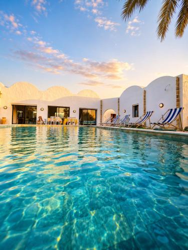 a pool at a resort with chairs in the water at Maison Ile d'Olive in Midoun
