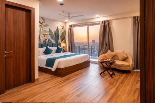a bedroom with a bed and a chair and a window at Hibiscus Elite Hotel in Greater Noida