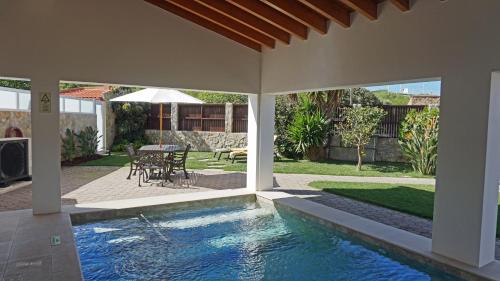 a swimming pool in a house with a table and chairs at Paradisus III in São Martinho do Porto