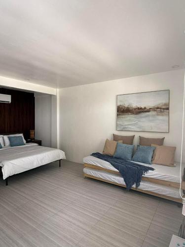 ein Schlafzimmer mit zwei Betten und einem Gemälde an der Wand in der Unterkunft The Beachfront Bataan in Morong