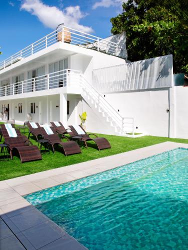 ein Haus mit Swimmingpool und Stühlen und ein Gebäude in der Unterkunft The Beachfront Bataan in Morong