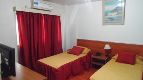 1 dormitorio con 2 camas y cortina roja en Adrazi Internacional en Buenos Aires