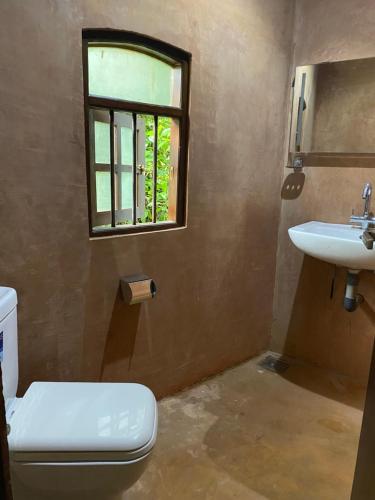 a bathroom with a toilet and a sink and a window at Farm House Villa in Ratnapura