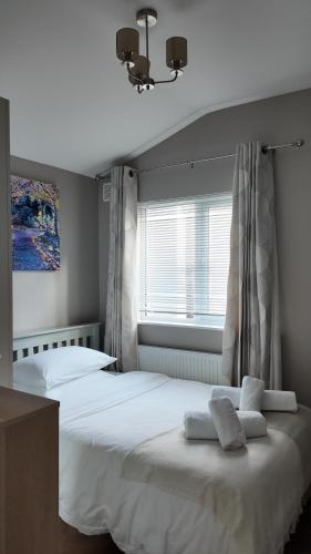 a bedroom with a large white bed and a window at Little Cottage Oassis in Dublin