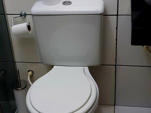 a white toilet in a bathroom with a roll of toilet paper at Nosso Cantinho no interior in Lençóis