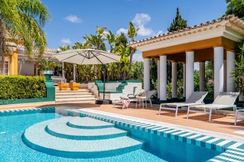 a pool with chairs and an umbrella next to a house at CICAS VILLA in Albufeira