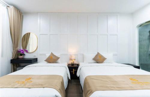 a hotel room with two beds and a mirror at HoangAnh Hotel in Ha Long