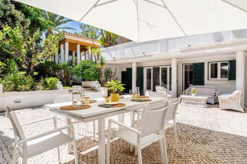 an outdoor dining room with a white table and chairs at CICAS VILLA in Albufeira