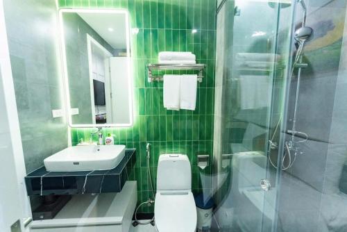 a green tiled bathroom with a toilet and a sink at HoangAnh Hotel in Ha Long