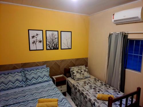 two beds in a bedroom with yellow walls at Nosso Cantinho no interior in Lençóis