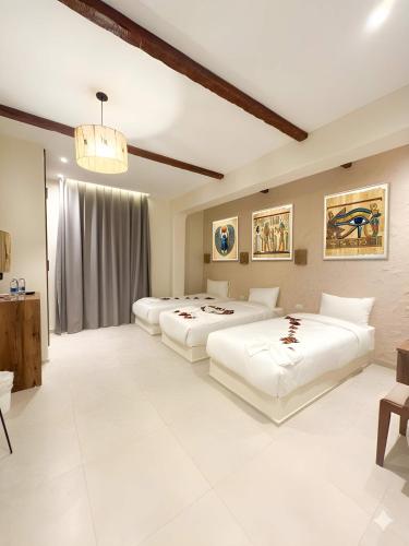 two beds in a large room with white at Pyramids Spiritual Hotel in Cairo