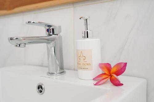 a bathroom sink with a bottle of soap and a flower at Royal Crown Villas in Ungasan
