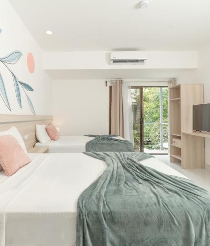 a white bedroom with two beds and a tv at Wide Mouth Frog Quepos in Manuel Antonio