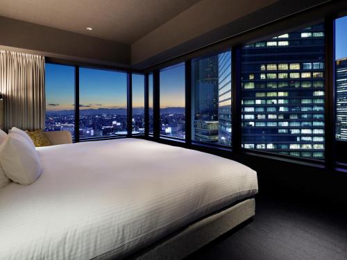 a bedroom with a large bed and large windows at Mitsui Garden Hotel Nagoya Premier in Nagoya