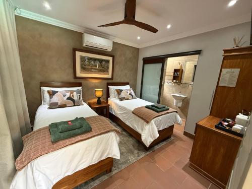 a bedroom with two beds and a bathroom at Be Our Guest Accommodation in Klerksdorp