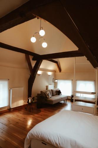 a bedroom with a bed and a couch in a room at B&B De Mout in Diest