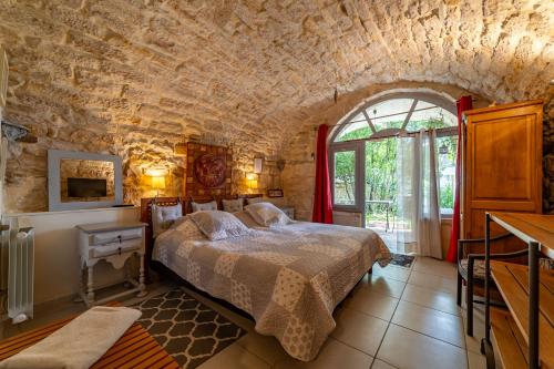 a bedroom with a bed in a stone wall at Mas Escombelle in Barjac